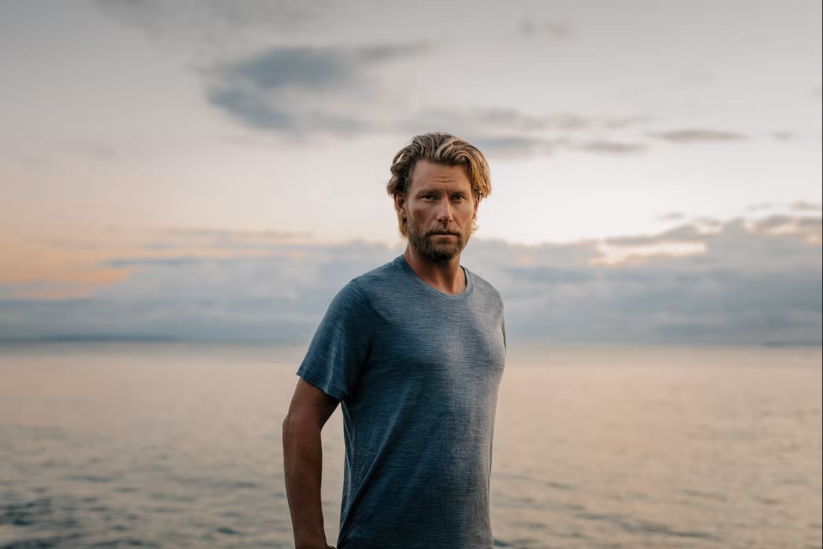 Bild Mann schaut in die Kamera mit Wasser im Hintergrund